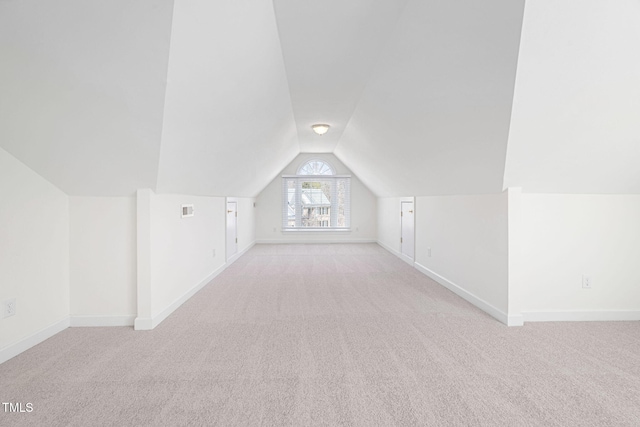 additional living space with lofted ceiling, light colored carpet, baseboards, and visible vents