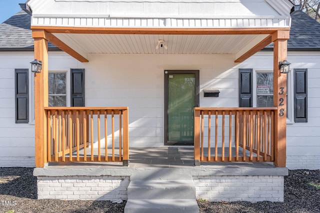 property entrance featuring covered porch and roof with shingles