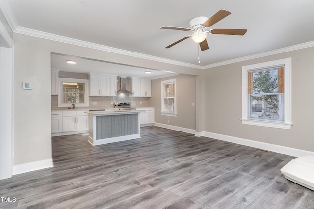 kitchen with light countertops, backsplash, white cabinets, stainless steel range with electric stovetop, and wall chimney exhaust hood