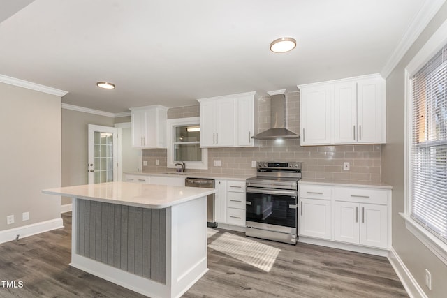 kitchen with dark wood-style floors, crown molding, stainless steel appliances, light countertops, and wall chimney exhaust hood