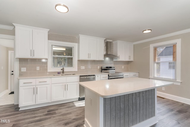 kitchen featuring a sink, appliances with stainless steel finishes, wall chimney range hood, and crown molding