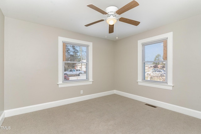 empty room with a wealth of natural light, baseboards, visible vents, and carpet