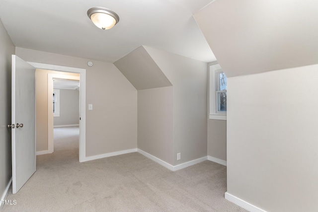 additional living space with lofted ceiling, light carpet, and baseboards