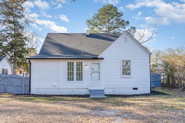 rear view of property with entry steps, roof with shingles, crawl space, a gate, and fence