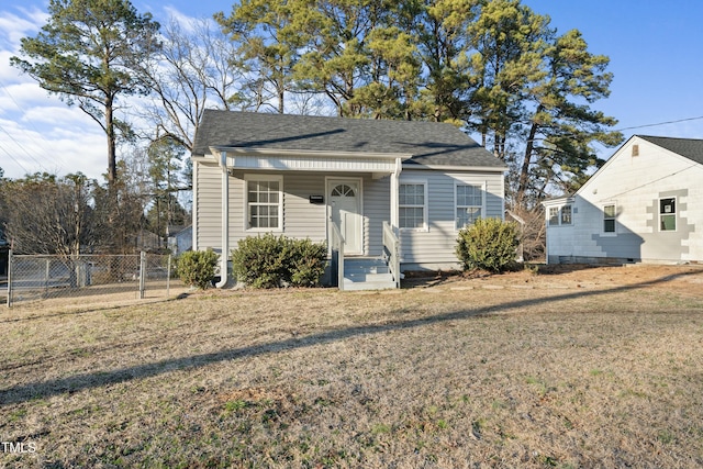 bungalow-style house featuring roof with shingles, a gate, fence, and a front yard