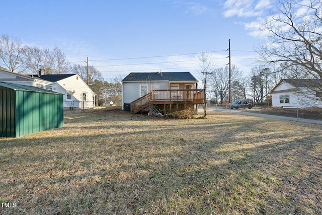 rear view of house featuring fence, stairway, a wooden deck, and a lawn