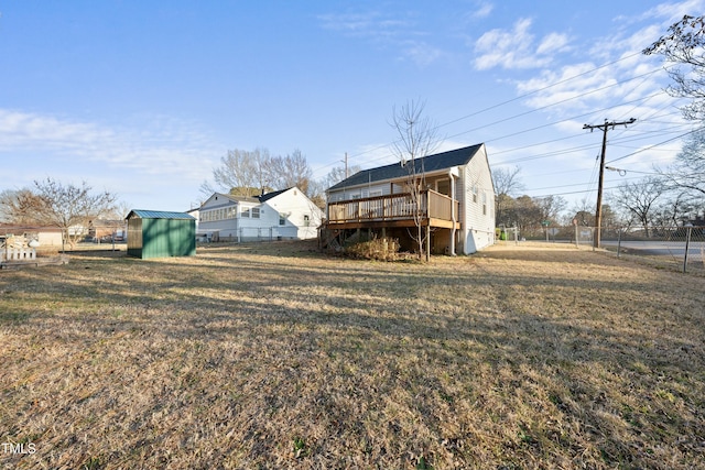 view of yard with a shed, fence, a deck, and an outbuilding