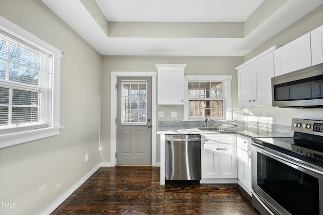 kitchen featuring dark wood-style floors, light stone counters, stainless steel appliances, and a wealth of natural light