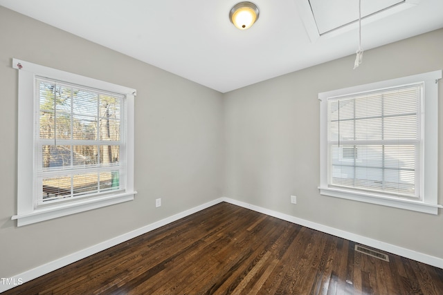 spare room featuring baseboards, a healthy amount of sunlight, visible vents, and attic access