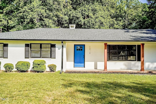 ranch-style home with a front lawn, a shingled roof, and brick siding