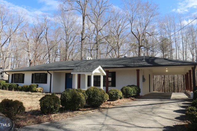 ranch-style home featuring an attached carport, roof with shingles, driveway, and stucco siding