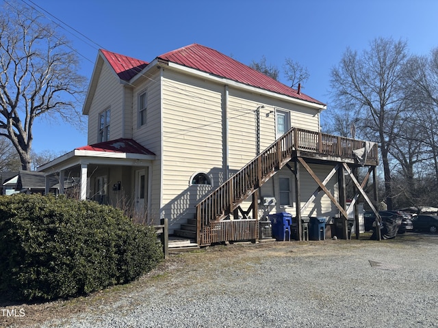 view of side of home with metal roof, a deck, and stairs