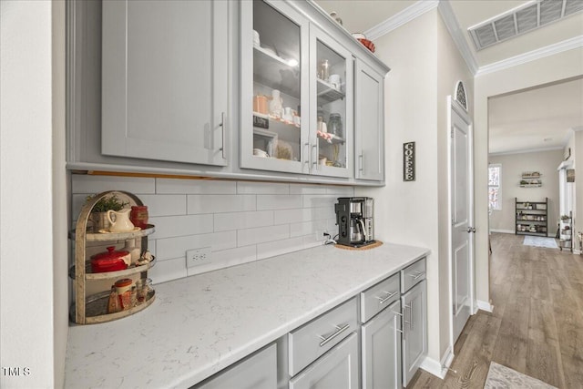 bar featuring visible vents, light wood-type flooring, crown molding, and decorative backsplash