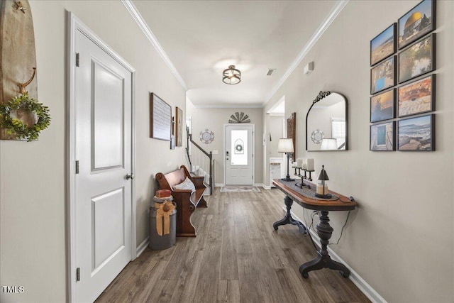 foyer entrance with stairs, wood finished floors, baseboards, and ornamental molding