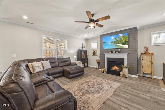 living room with crown molding, baseboards, light wood-type flooring, and ceiling fan