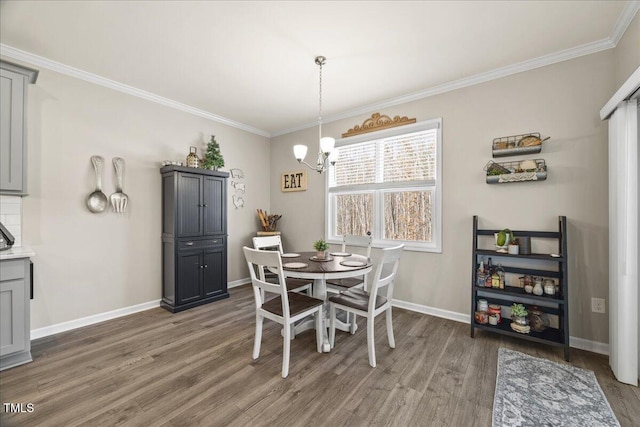 dining area featuring an inviting chandelier, crown molding, wood finished floors, and baseboards