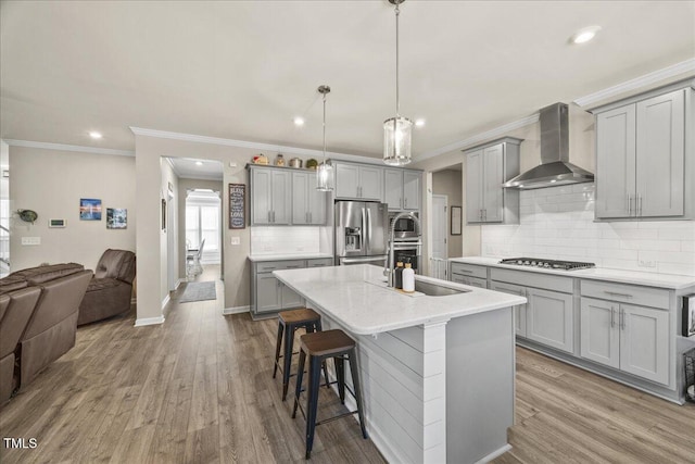 kitchen with a sink, gray cabinetry, appliances with stainless steel finishes, wall chimney range hood, and open floor plan