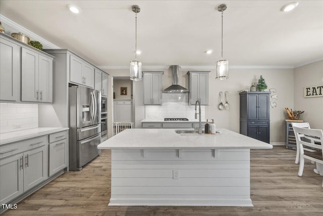 kitchen with gray cabinets, appliances with stainless steel finishes, wall chimney range hood, and a sink