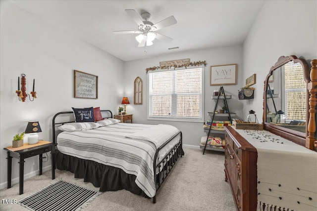 bedroom featuring visible vents, light colored carpet, baseboards, and ceiling fan