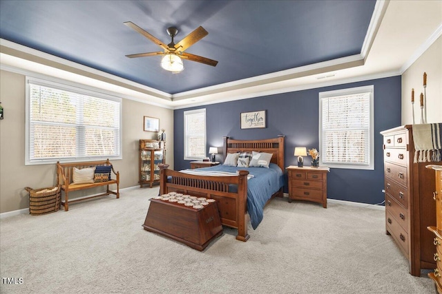 carpeted bedroom featuring a ceiling fan, a raised ceiling, baseboards, and ornamental molding