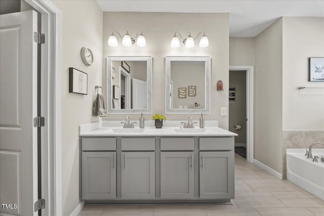 full bathroom featuring a garden tub, double vanity, baseboards, and a sink