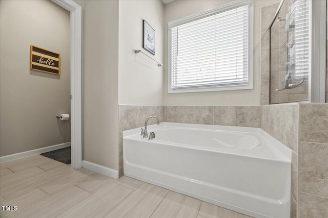 full bath with a bath and baseboards