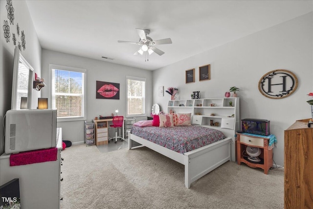 carpeted bedroom with visible vents, baseboards, and a ceiling fan