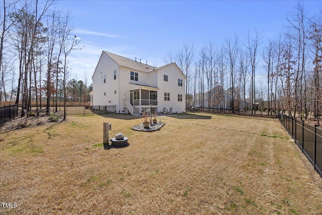 rear view of property featuring a lawn, a fenced backyard, and a sunroom