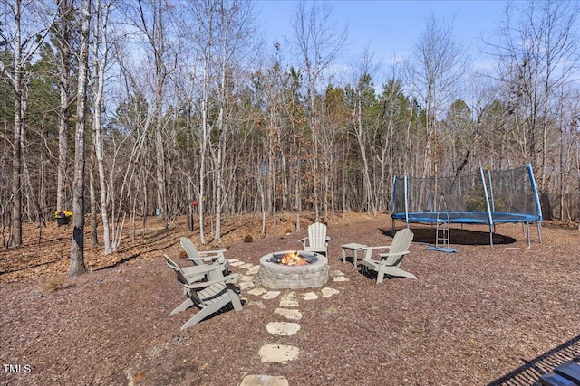 view of yard featuring a fire pit and a trampoline