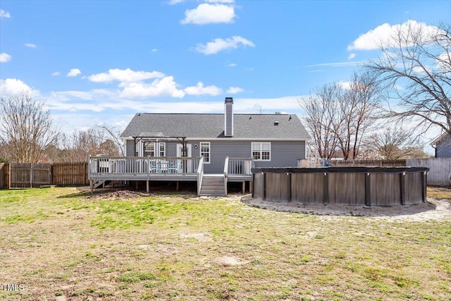 rear view of house featuring a fenced backyard, a pool, a yard, a wooden deck, and a chimney