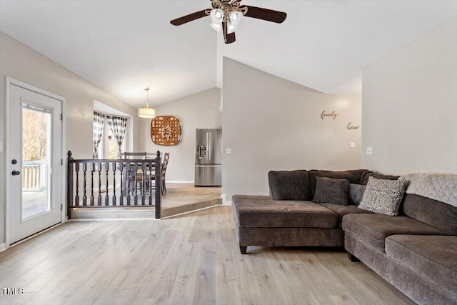 living area featuring vaulted ceiling, ceiling fan, baseboards, and light wood-style floors