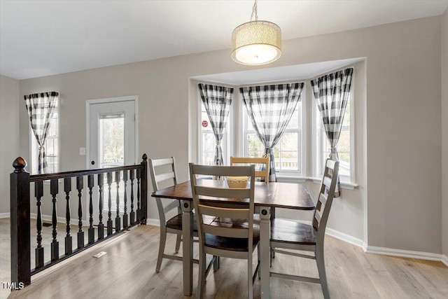 dining room featuring a healthy amount of sunlight, light wood-style flooring, and baseboards