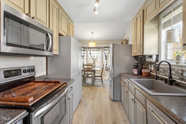 kitchen with stainless steel appliances, dark countertops, a sink, and plenty of natural light