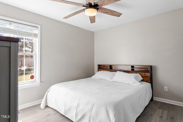 bedroom with wood finished floors, a ceiling fan, and baseboards