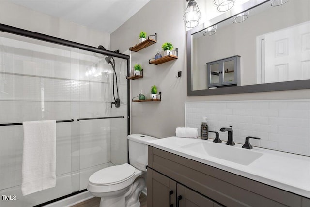 bathroom featuring toilet, a stall shower, tasteful backsplash, and vanity