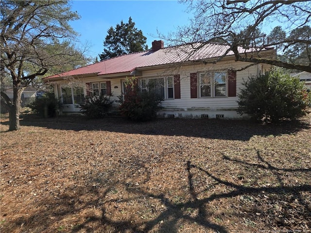 view of front of house featuring crawl space, a chimney, and metal roof