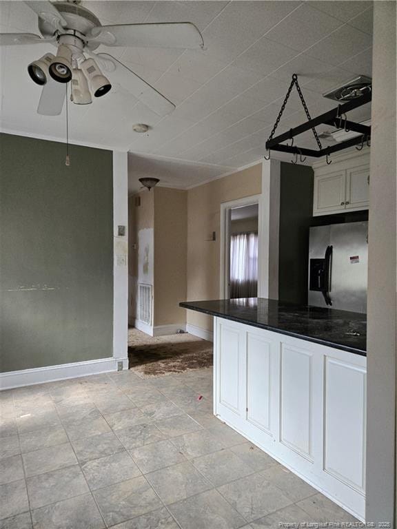 kitchen with dark countertops, stainless steel fridge with ice dispenser, a ceiling fan, white cabinetry, and baseboards