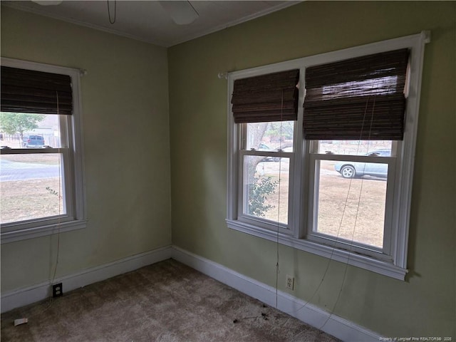 carpeted empty room with crown molding, baseboards, and ceiling fan