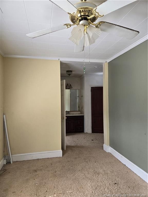 carpeted empty room with ceiling fan, baseboards, and ornamental molding