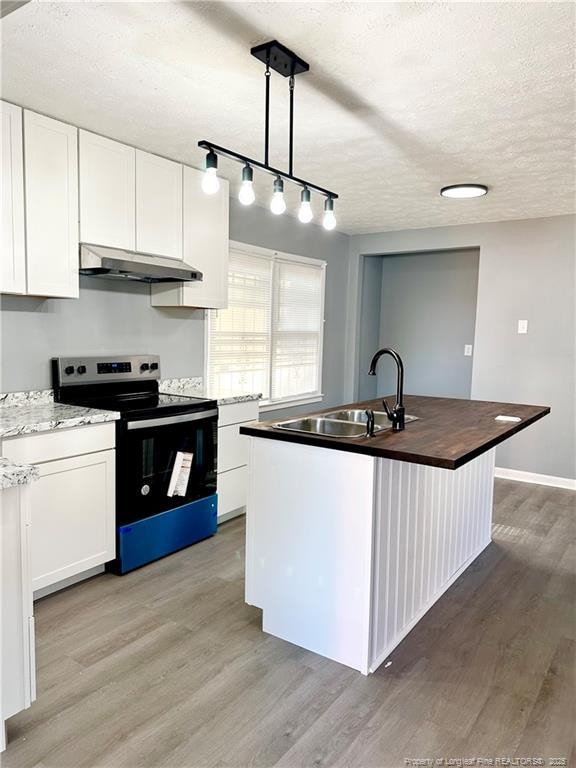 kitchen with electric range, light wood-style flooring, a textured ceiling, under cabinet range hood, and a sink