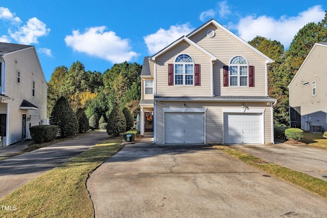 view of front of home with central air condition unit, driveway, and a garage