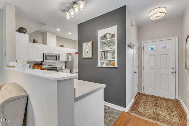 kitchen featuring light countertops, appliances with stainless steel finishes, white cabinetry, and decorative backsplash