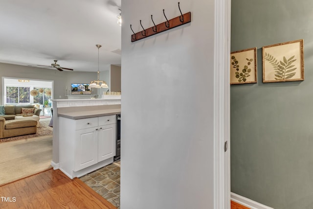 corridor featuring light wood-type flooring, beverage cooler, and baseboards