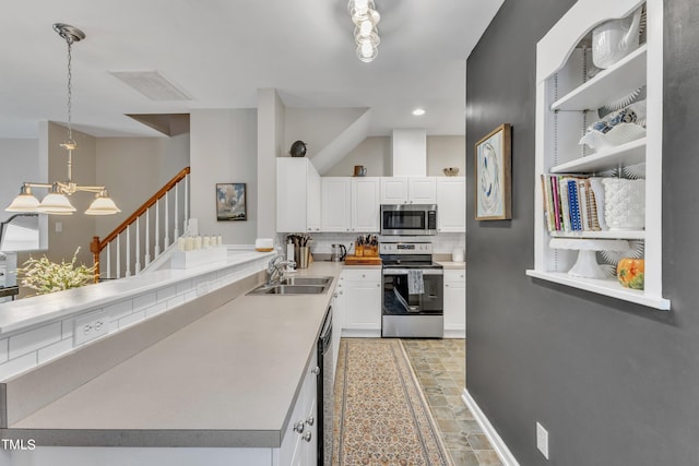 kitchen featuring stainless steel appliances, tasteful backsplash, white cabinets, a sink, and a peninsula