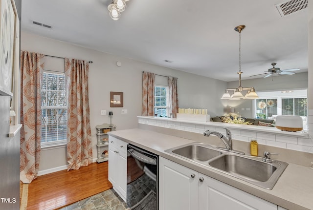 kitchen featuring white cabinetry, black dishwasher, visible vents, and a sink