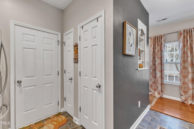 entrance foyer featuring baseboards, visible vents, and stone finish flooring