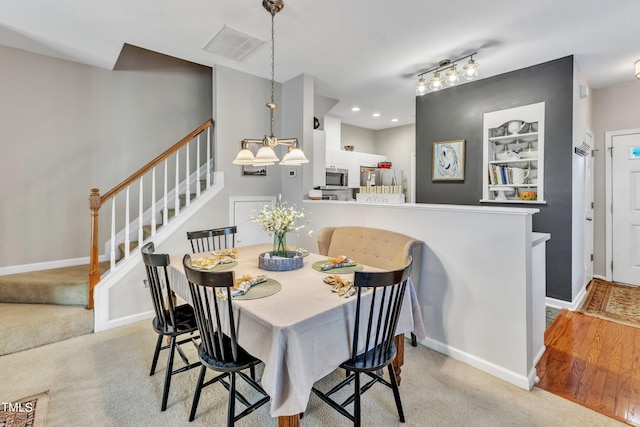 dining area with light carpet, baseboards, visible vents, and stairway