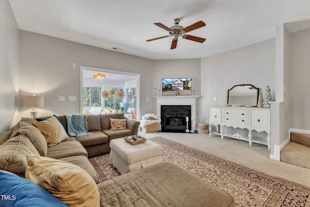 living room featuring visible vents, baseboards, a fireplace with flush hearth, ceiling fan, and carpet floors