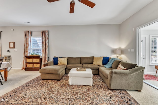 living area with baseboards, a ceiling fan, and light colored carpet