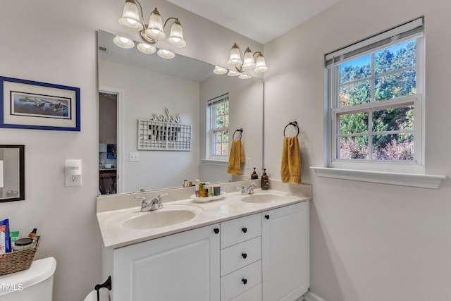 full bath with toilet, double vanity, and a sink